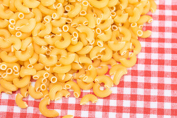 Scattered Uncooked Chifferi Rigati Pasta on Red Checkered Towel. Fat and Unhealthy Food. A Heap of Classic Dry Macaroni. Italian Culture and Cuisine. Raw Pasta