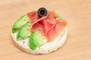 Rice Cake Sandwich with Fresh Avocado, Jamon and Olives on Bamboo Cutting Board. Easy Breakfast....