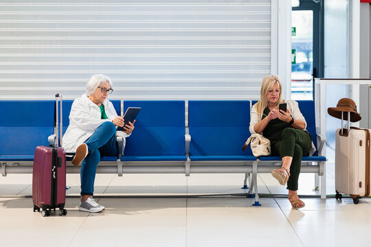 Women waiting for boarding with gadgets