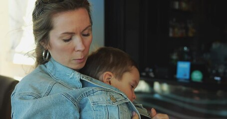 Young elegant mother wrap five year old son in jacket to warm on cold autumn day. Moments of tenderness and care between parent and small child.