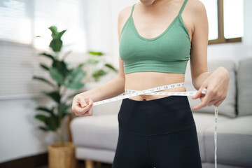 Asian healthy woman dieting Weight loss. Slim woman measuring waist with measure tape after diet at...