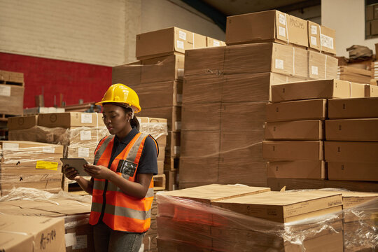 Young African female warehouse worker doing inventory using a tablet