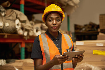 Young African female warehouse worker doing inventory with a tablet