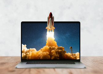 Laptop on the desktop and the space shuttle rocket successfully takes off beyond the frames of...