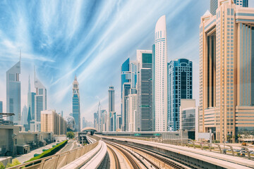 Metro road among glass skyscrapers in Dubai. Metropolitan railway among glass skyscrapers in Dubai. Traffic on street in Dubai. Modern with skyscrapers architecture of Dubai, UAE. Altered sky.