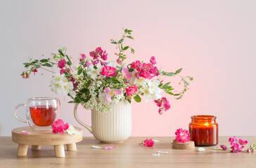 summer flowers, burning candles and cup of tea   on light background