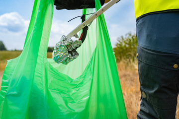 Young volunteer picking up litter in the nature