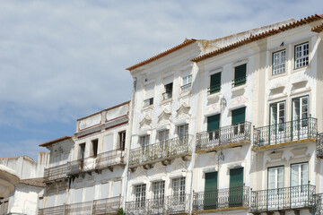 Fototapeta na wymiar Old historical buildings with shabby facades of white and beige colours downtown Evora, Portugal. Conceptual for protection, restoration and renovation