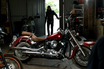 Creative authentic motorcycle workshop Garage bearded biker mechanic enters the premises before starting work