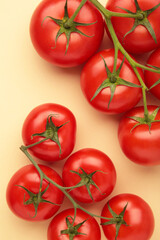 Flat lay composition with bunch of tomatoes on beige background. Vertical photo.