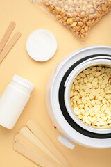 Electric wax warmer or wax heater with wax drops inside on beige background. Vertical photo.