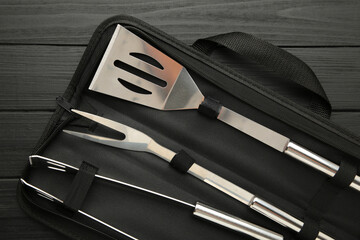 Barbecue accessories in black case on dark wooden background.