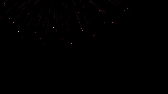 Single color fireworks repeatedly explode against night sky. Red color fireworks explode in circle shape against late night dark sky