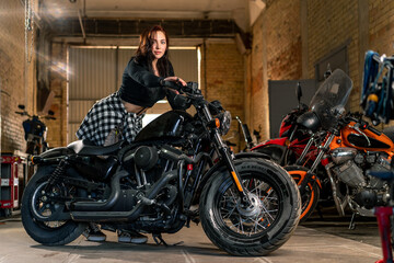Fototapeta na wymiar Creative authentic motorcycle workshop garage beautiful young girl biker sitting on a cool motorcycle