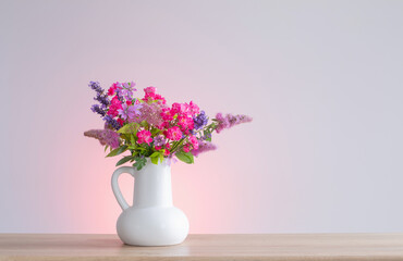 beautiful flowers in white jug on wooden shelf