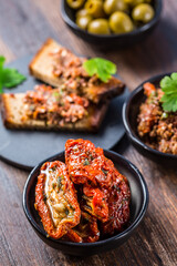 Sun dried tomatoes in olive oil and crostini with tapenade and ingredients.