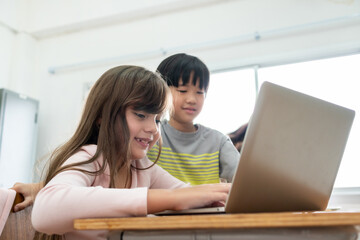 Diversity MultiEthnic Elementary school boy and girl using laptop.
