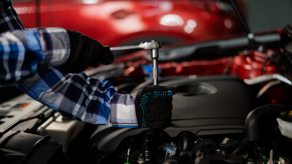 Female auto mechanic unscrewing a nut to replace a car spark plug.