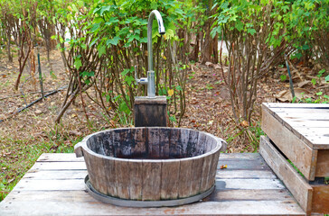 Country style water faucet with wooden bucket sink in the garden