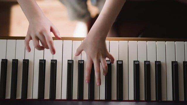 Girl musician plays composition with notes of shortened duration. Schoolgirl improves piano playing techniques in class upper view on blurred background