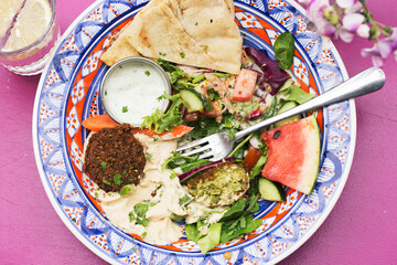 Summer arabic salad with falafel, hummus, water melon, carrots, lettuce, carrots, dressing and pita bread  - 615534371