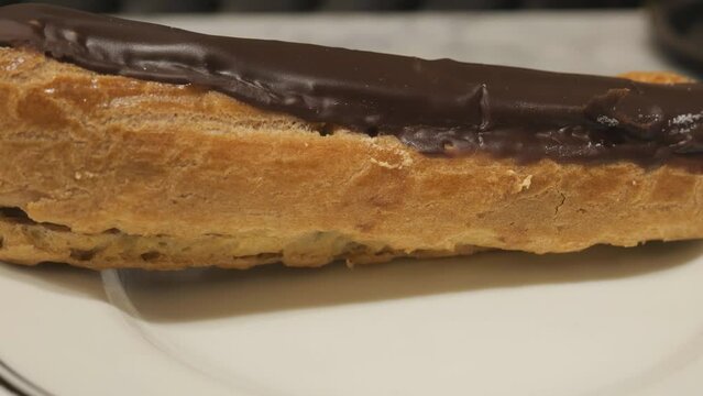 A close up shot of a chocolate eclair on a plate.