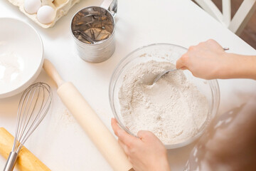 Top view of mixing flour in a bowl  on a white homemade table. The concept of home baking. Step by step .