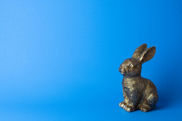 Golden rabbit figurine on the blue background. Free space