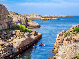 Archipelago islands on the west coast of Sweden - a canoe paddler paddles out of the channel at...
