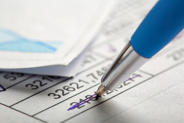 Accounting document with pen, money, coins and checking financial chart. Concept of banking, financial report and financial audit.