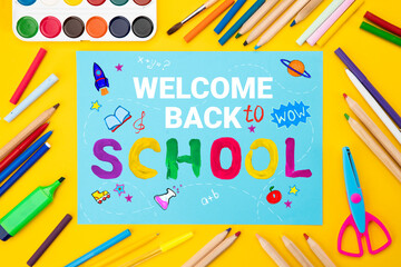 Back to school background. Top view flat lay concept. Childish lettering, colored paper, supplies, stationery for primary school, elementary school or grade school or preschool educational