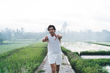 Positive ethnic man pointing at camera in nature