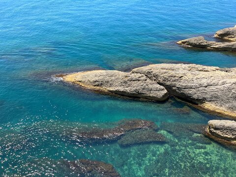 Sea turquoise blue water with shiny surface and coastal rocks.