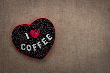 Love Coffee concept image with copy space, beautiful coffee beans in a heart shaped box isolated on jute texture background