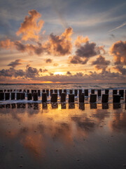 Sunset with colorful sky and clouds and wooden posts at Westenschouwen, Zeeland, the Netherlands