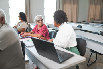 mulheres Brasileiras usando computador portátil durante aula em uma classe para adultos e idosos...