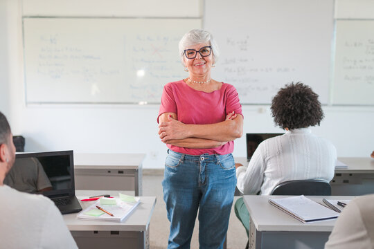 retrato de uma mulher Brasileirana terceira idade de cabelos brancos de bra&ccedil;os cruzados sorrindo na sala de aula no Brazil