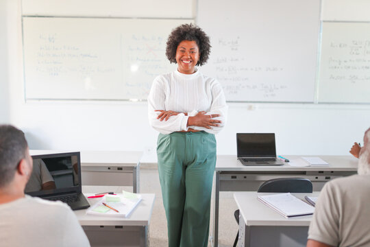 retrato de uma mulher adulta Brasileira sorrindo de bra&ccedil;os cruzados na sala de aula em um curso para adultos no Brasil