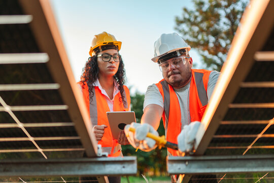 t&eacute;cnicos vestindo equipamentos de prote&ccedil;&atilde;o instalando pain&eacute;is de energia fotovoltaica em uma propriedade rural no Brasil