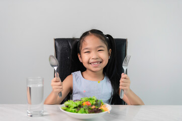 Little asian cute girl to eat healthy vegetables.Nutrition and healthy eating habits for kids...