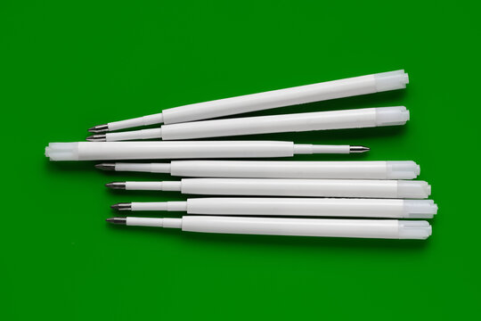 Plastic refills for ballpoint pens. Ballpoint pen refills. White ink refills on a green
