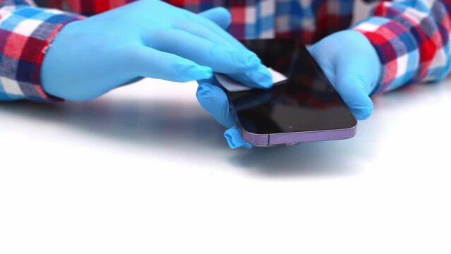 A male master glues a protective glass on a smartphone