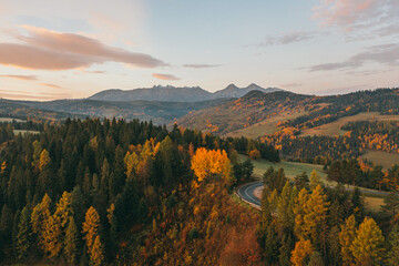 Sunny sunrise in autumn mountains. Mountains in a fog illuminated by rising sun. Autumn landscape with vivid sunlight. 