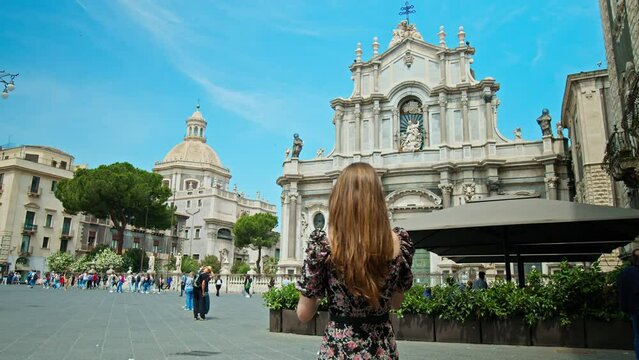 A beautiful woman visiting Basilica Cattedrale di Sant'Agata in Catania, Italy. Fashionable girl exploring the prominent baroque cathedral with its columned facade, domed roof, frescoes, and paintings