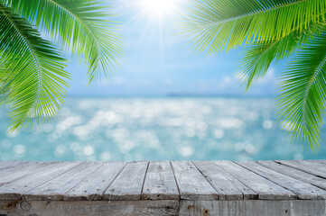 Empty wood table with seascape and palm leaves, blur bokeh light