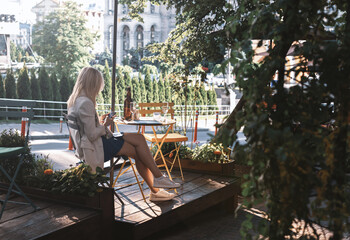 Obraz na płótnie Canvas Girl sits in a cafe on a summer terrace