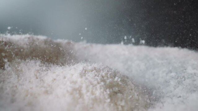 Powdered sugar bounces from vibrations on surface with concavity. Movement of white sweet powder. Food product prepared for use at cooking macro