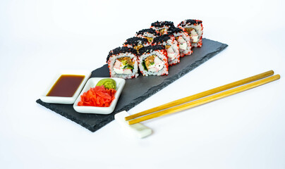 Sushi rolls on a black slate plate with soy sauce, ginger and wasabi. Japanese food, eating healthy