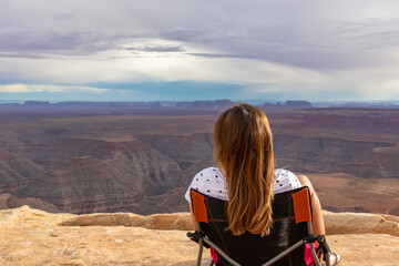 Woman sitting in camping chair enjoying scenic aerial vistas of desert landscape of Valley of the...