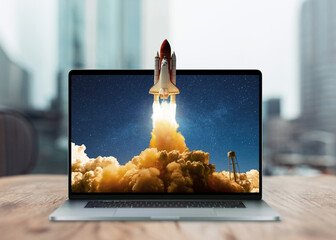 Space rocket shuttle with a cloud of smoke and blast takes off from a laptop on a working office...